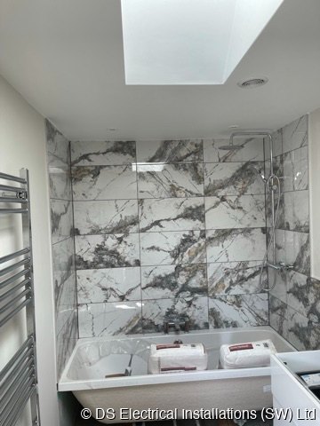 Marble tiled bathroom with rooflight, ceiling downlights and a chrome heated towel rail