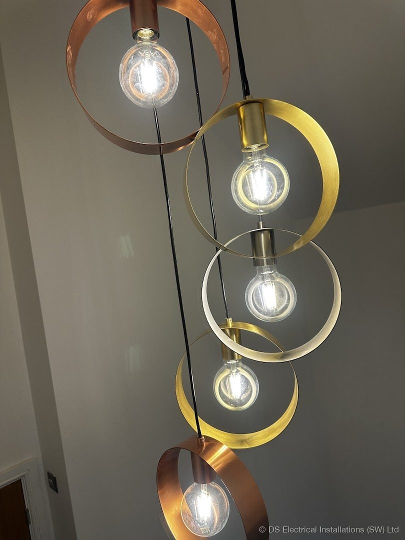 Cluster pendant light of copper and brass rings with exposed filament lamps