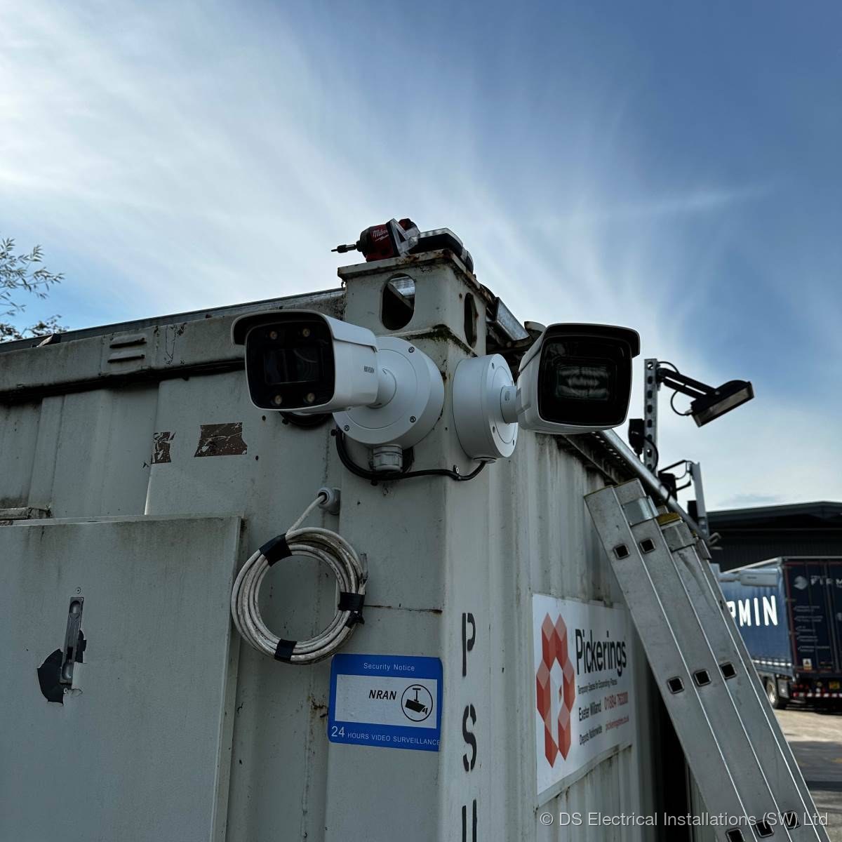 Twin bullet CCTV cameras on a bracket at the corner of a commercial yard building, installed by DS Electrical Installations (SW) Ltd