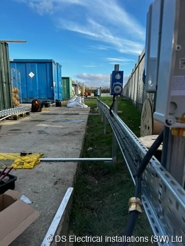 Galvanised cable basket containment run installed along a boundary fence on a commercial yard