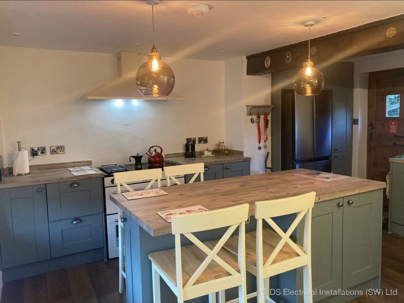 Shaker kitchen with glass pendant lights over a timber island, wired by DS Electrical Installations (SW) Ltd