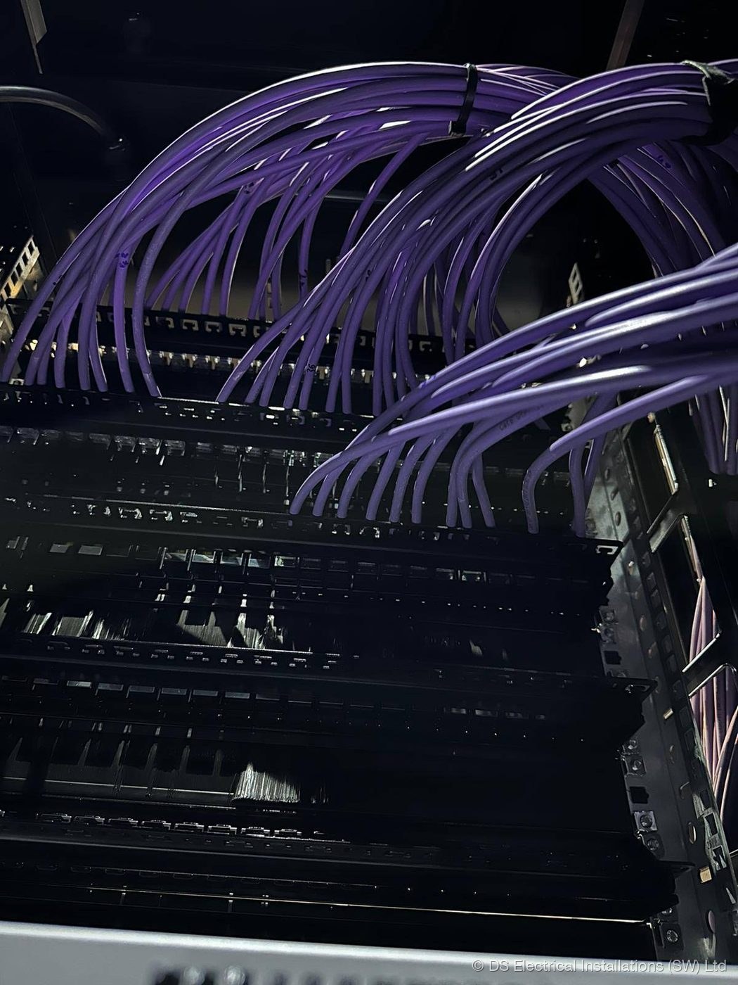 Cat6 cable tails combed and dressed into the rear of a patch panel in a comms rack