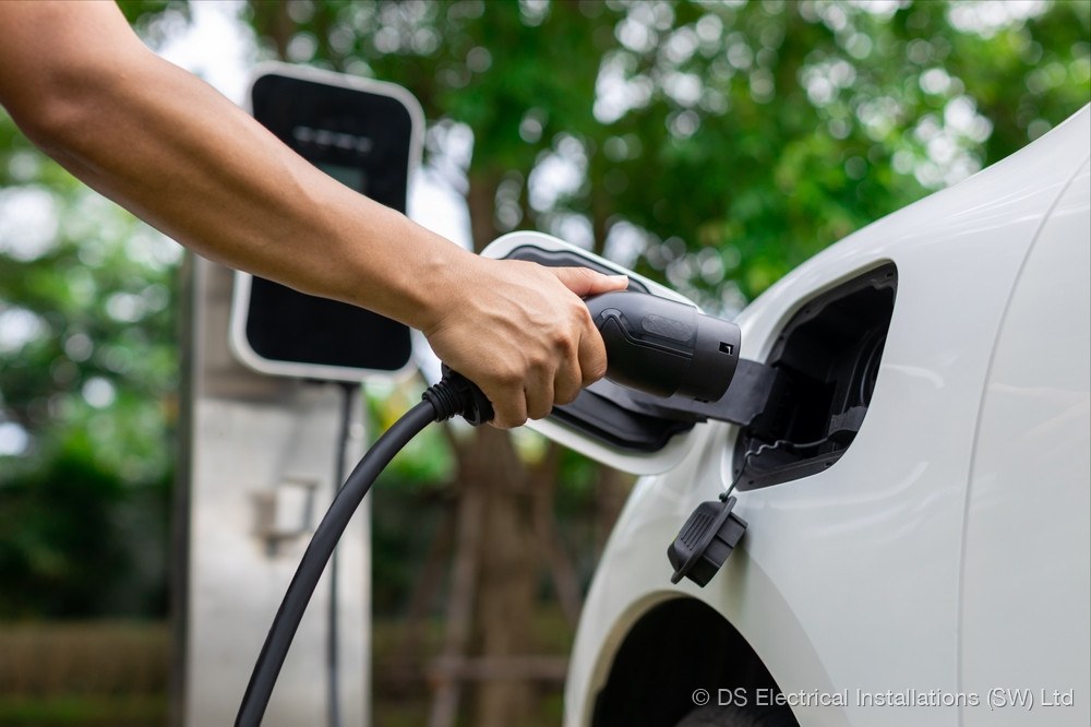 Electric vehicle being plugged in to a wall-mounted home charge point installed by DS Electrical Installations (SW) Ltd
