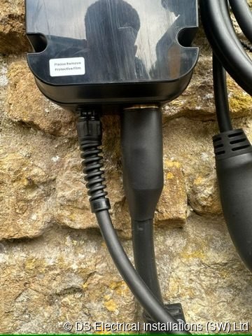 Tethered EV charging connectors holstered on a stone wall, installed by DS Electrical Installations (SW) Ltd