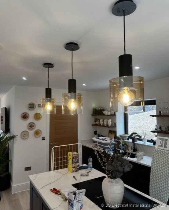 Modern grey kitchen with three black glass pendant lights wired over the island, Somerset