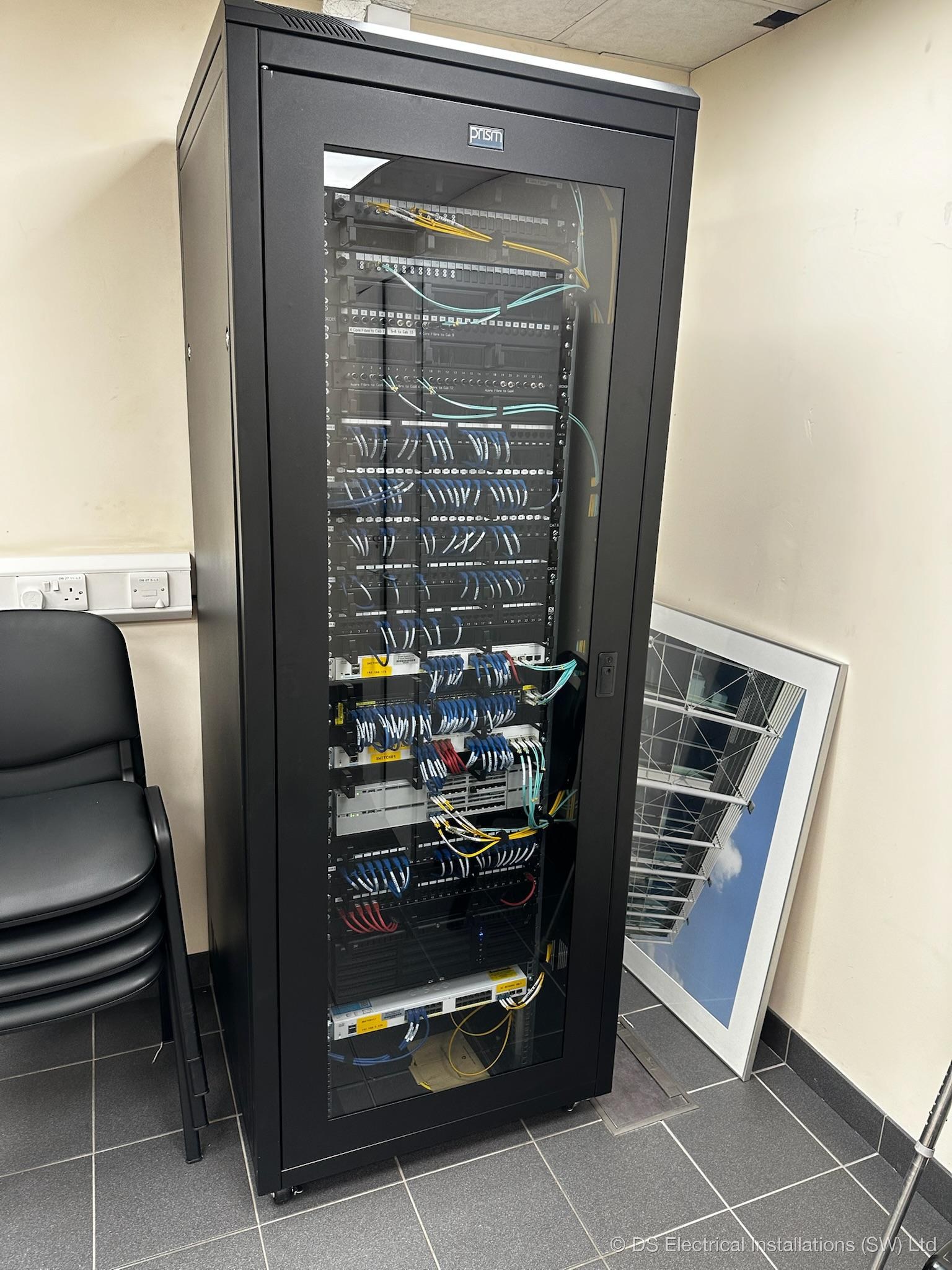 Floor-standing comms cabinet showing complete network infrastructure, Cat6, fibre, PoE switching, installed by DS Electrical