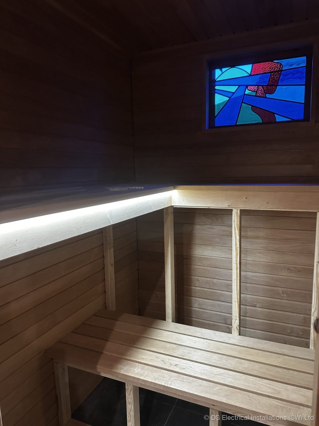 Concealed warm white LED strip run above bench seating in a timber-lined garden room